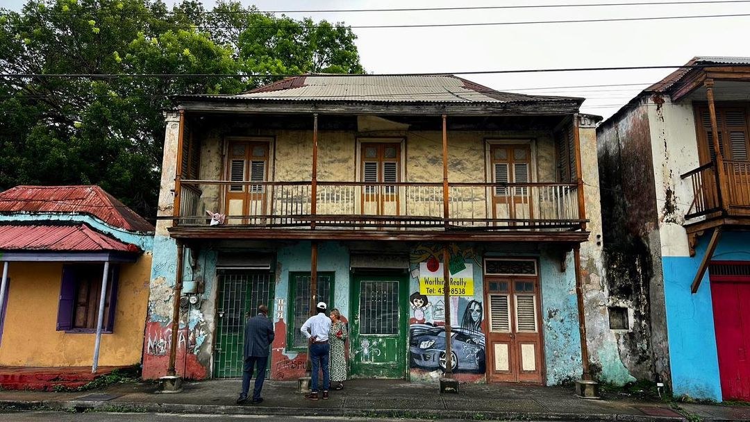 exterior of a two-story building with a balcony with graffiti or art on the first floor the building in need of preservation 