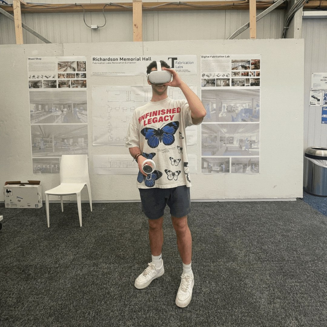 Student with a VR headset stands in front of a wall with images of the VR space inside the RMH renovation