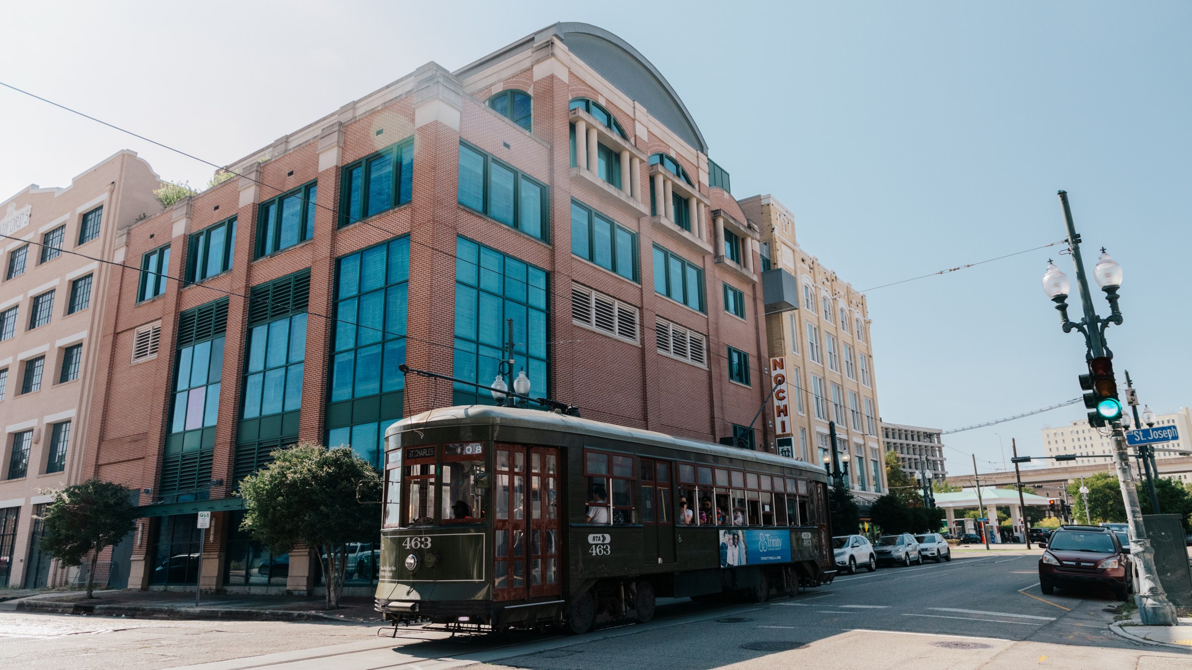 Exterior of five-story building on a corner in a downtown setting with a streetcar passing in the foreground