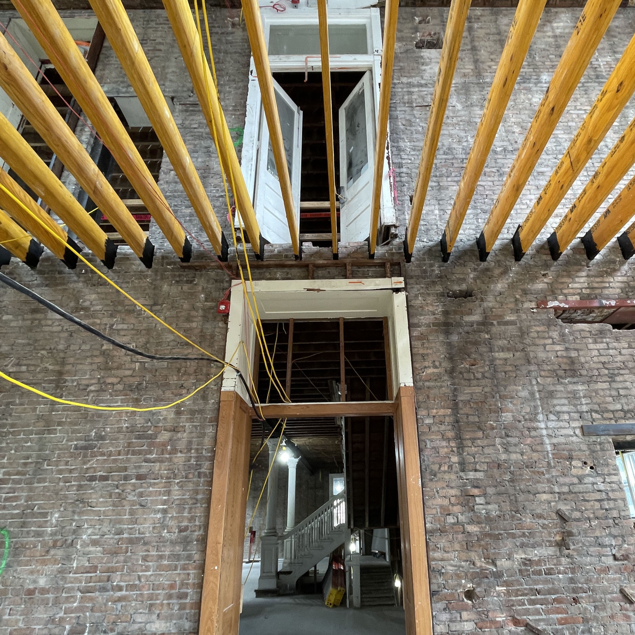 Interior photo of renovation of historic building, looking at a doorway and above at exposed floor beams above the doorway