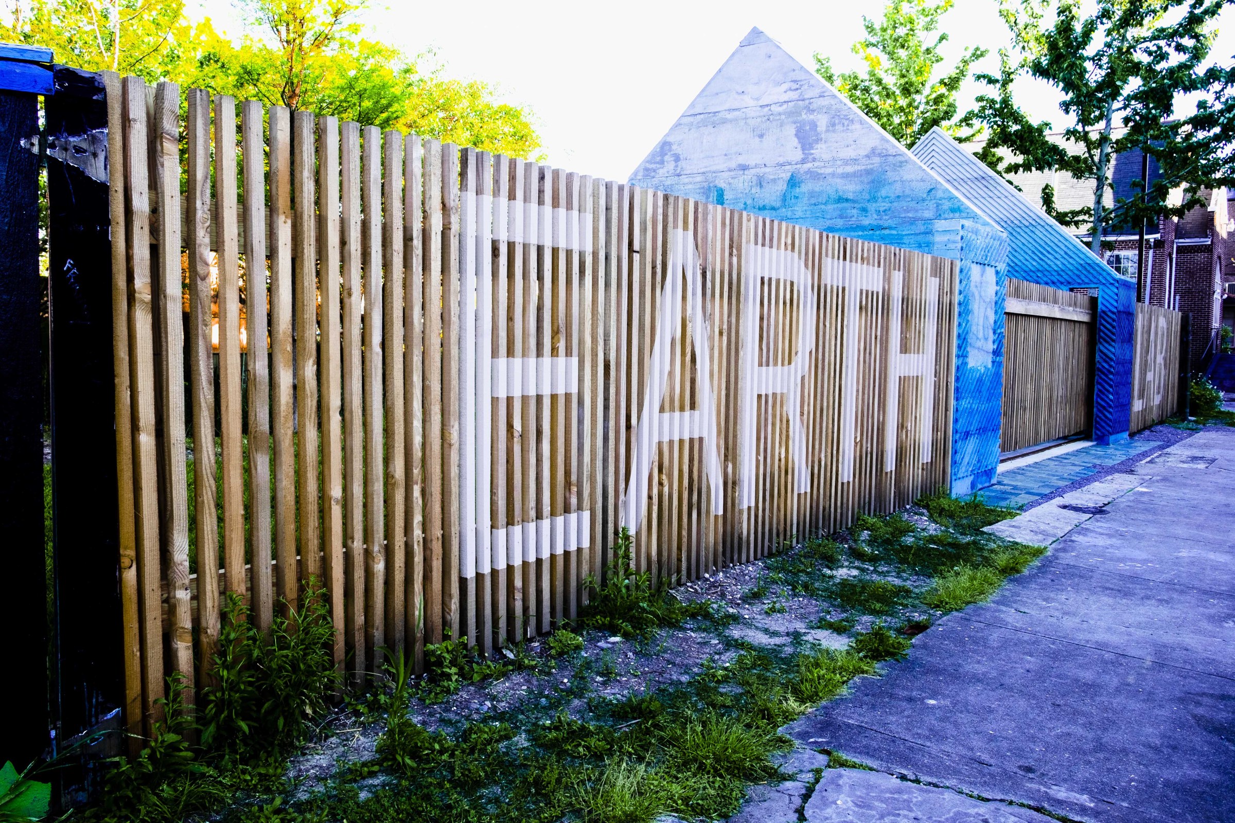 Photo of exterior of Earth Lab with Earth written in white writing in all caps across brown fence 