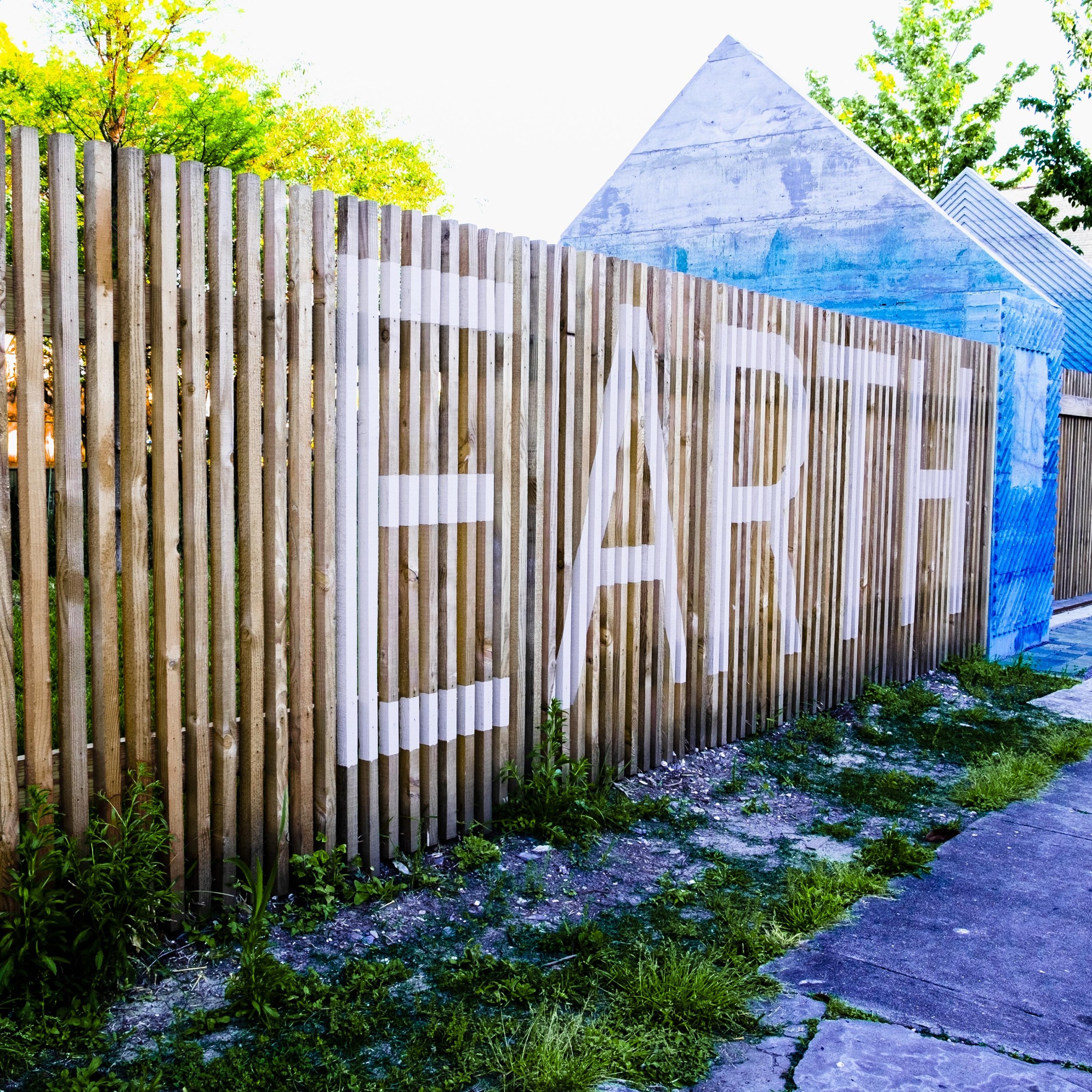 Photo of exterior of Earth Lab with Earth written in white writing in all caps across brown fence 