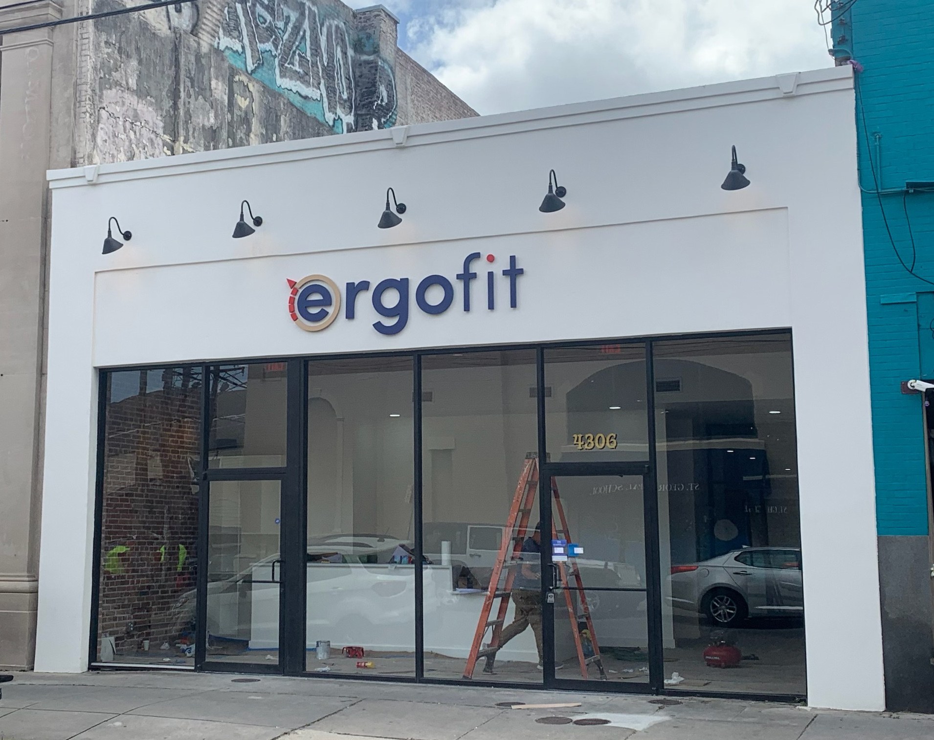 Photo of an exterior facade of one story retail space with the logo saying "ergo fit" above the storefront's large glass windows 
