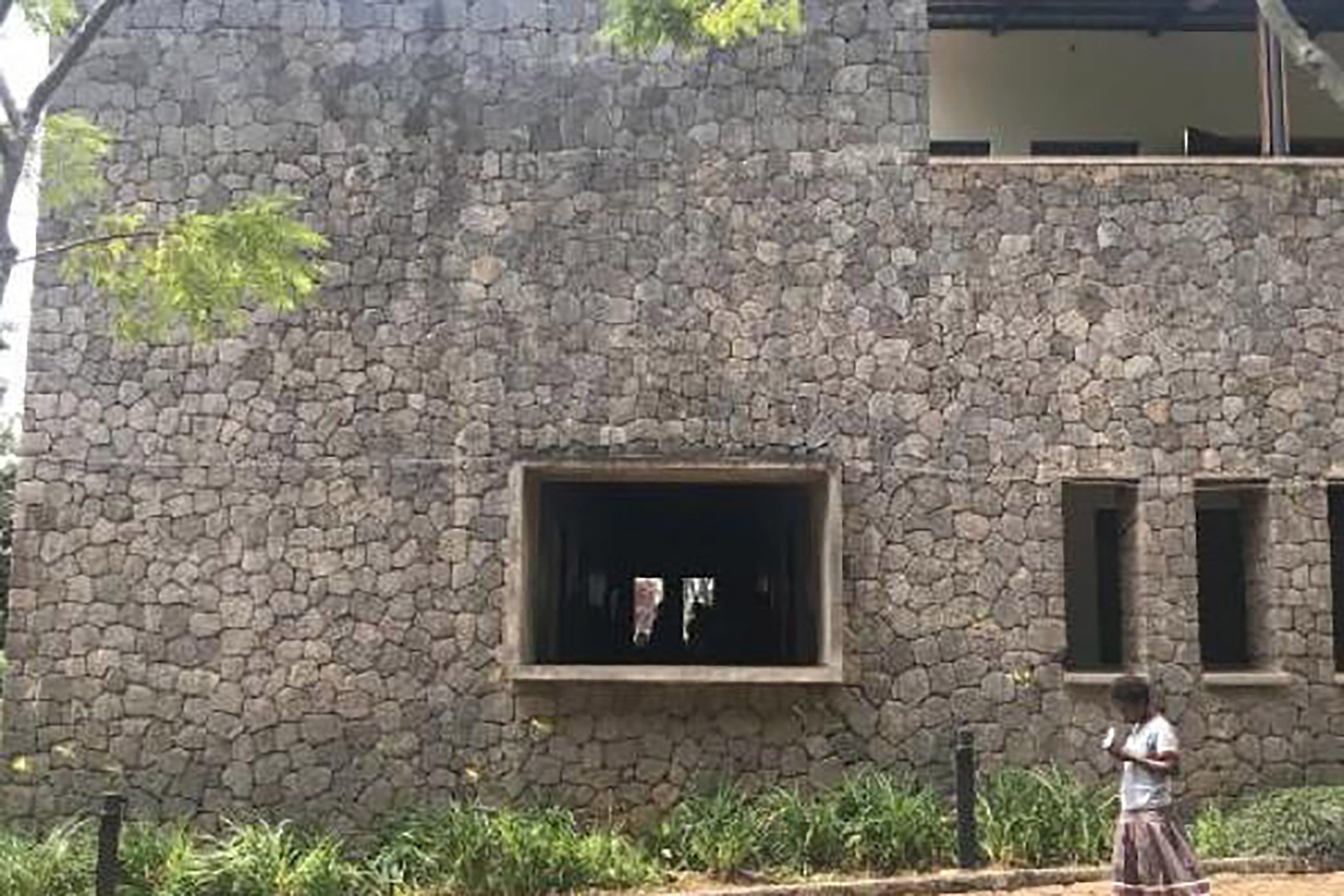 Photo of African woman walking by a cobblestone building