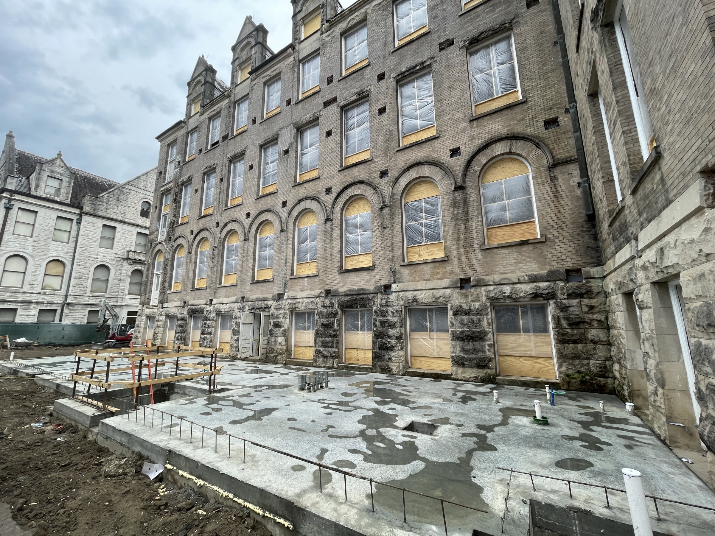 Exterior view of back facade at historic Richardson Memorial Hall with a new slab poured in the foreground, showing the footprint of the building's addition that will be built.