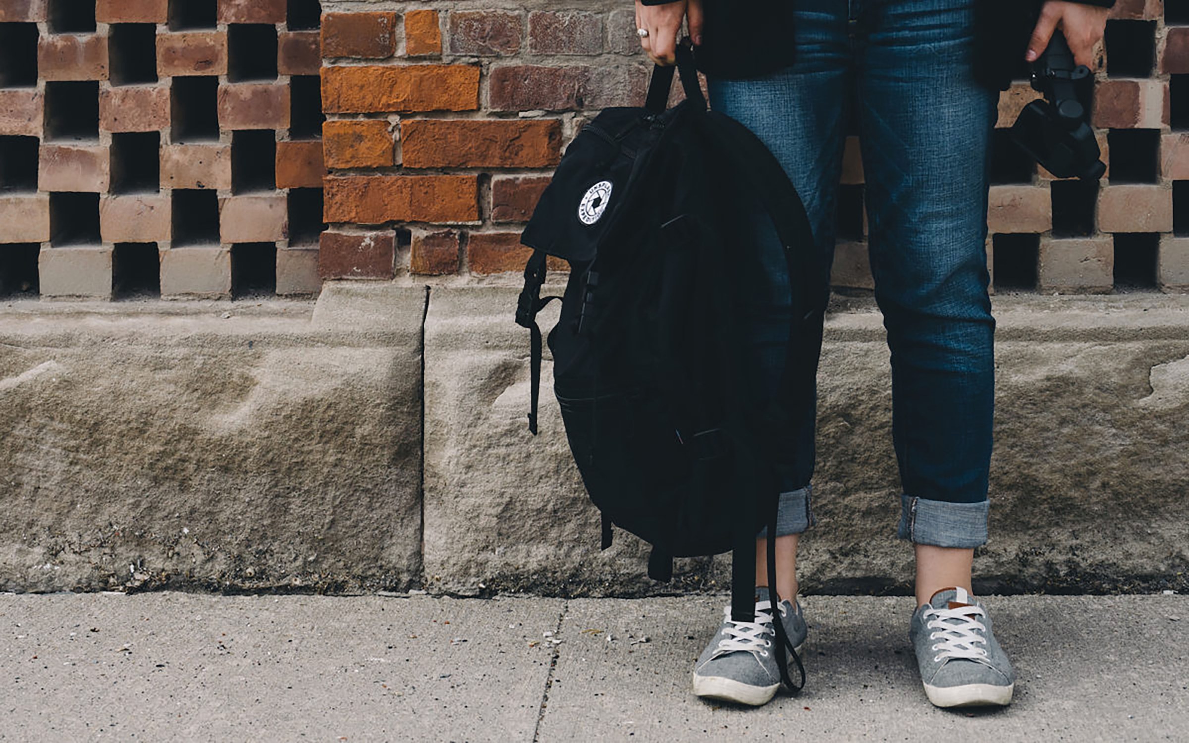 Photo of the legs of someone holding a backpack