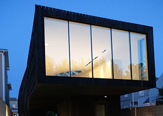 Photo of exterior of modern home with large floor to ceiling windows