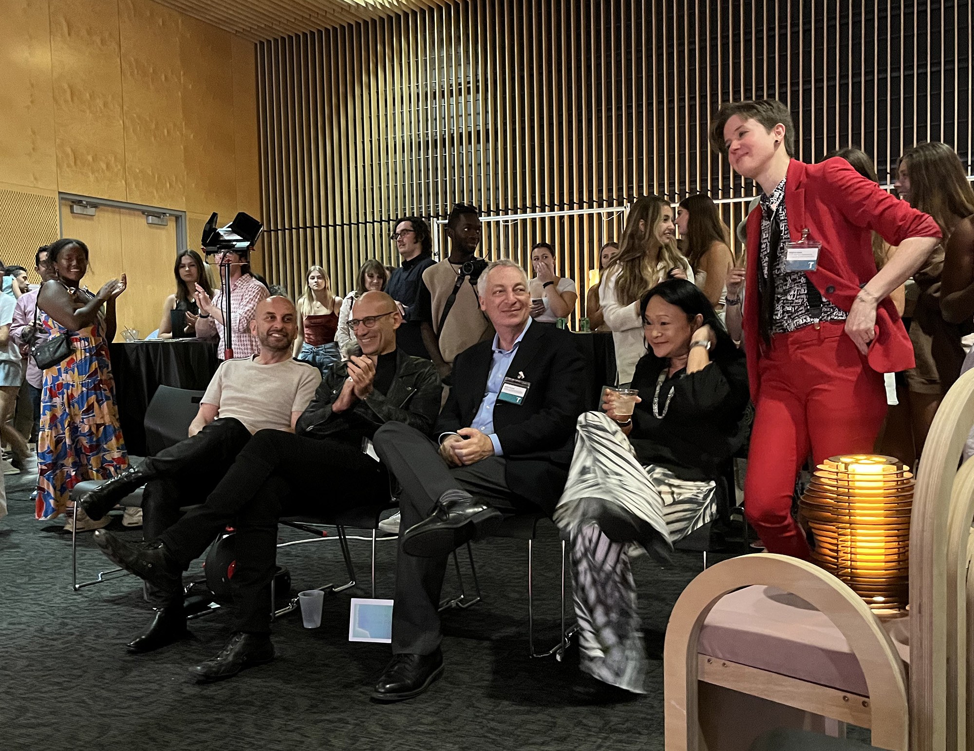 Five faculty and administrators sit and visit before the start of an indoor fashion show