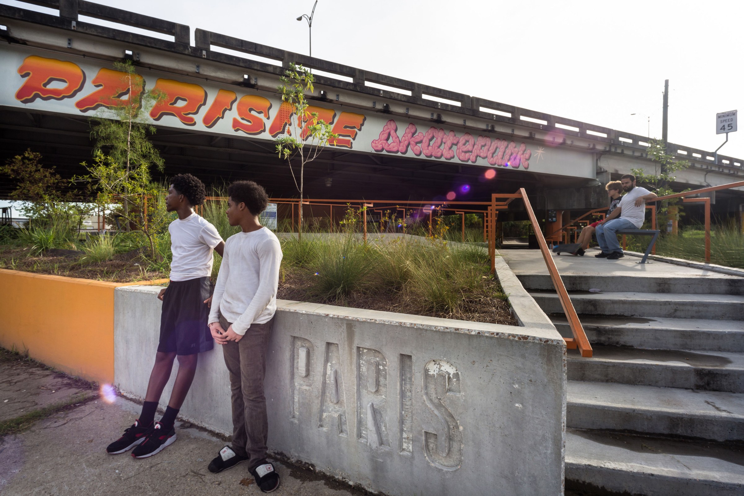 Two young boys standing in front of a concrete wall at Parasite Skatepark