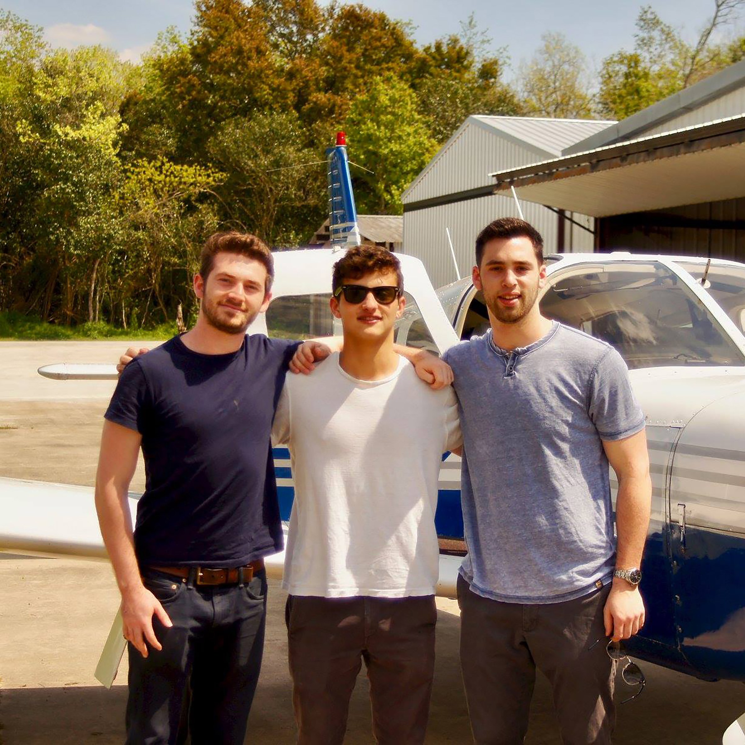 Photo of three students in front of a small propeller plane 