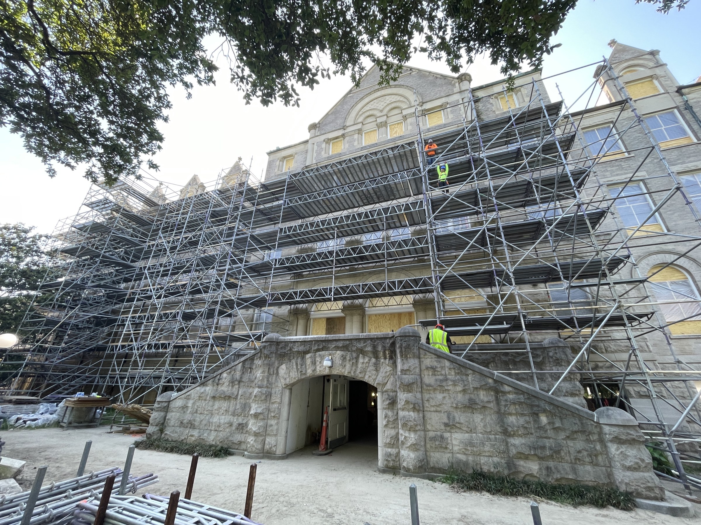 Exterior view of front facade of historic Richardson Memorial Hall with several stories of metal scaffolding built around the building's limestone facade.