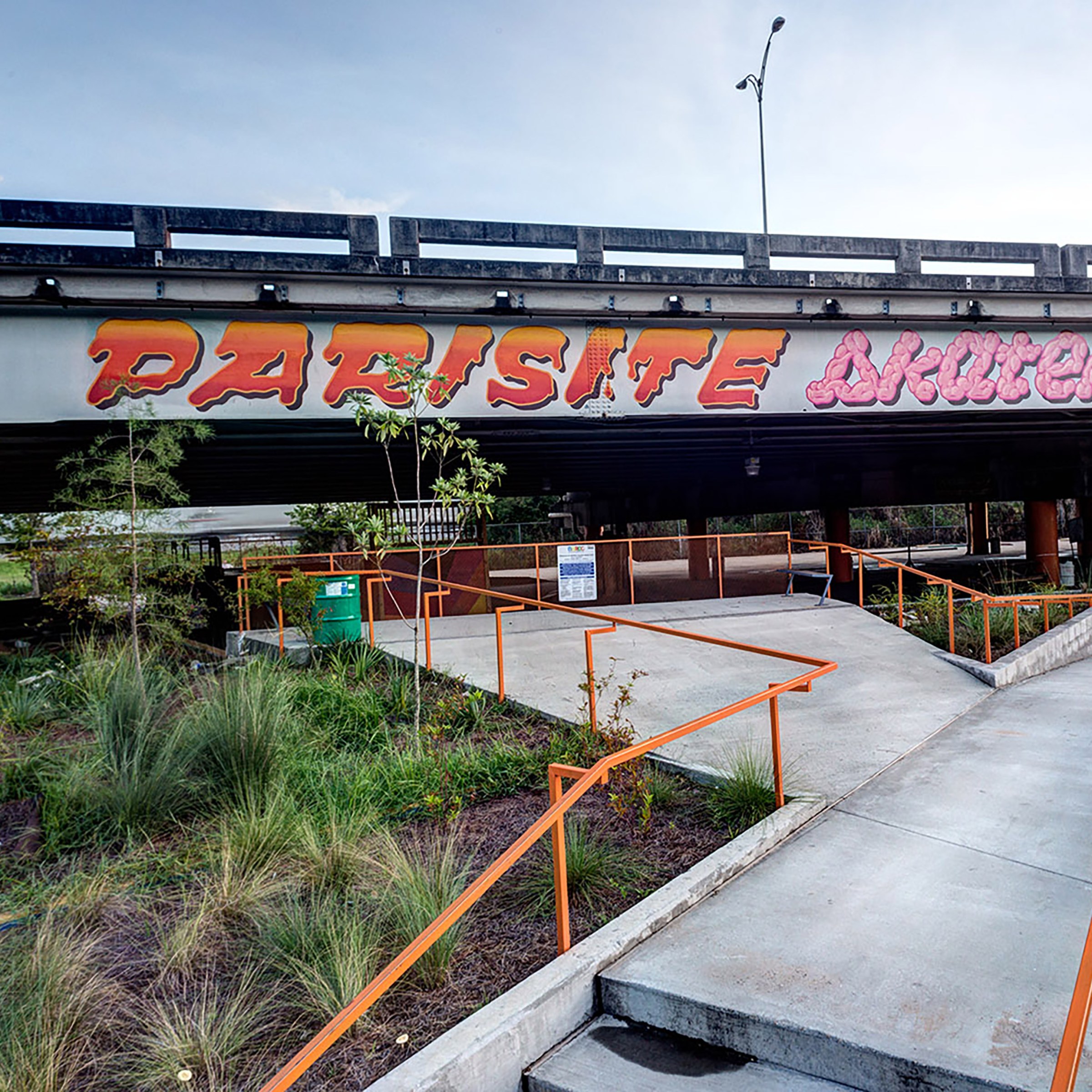 Photo of Parasite Skatepark with orange railings and greenery