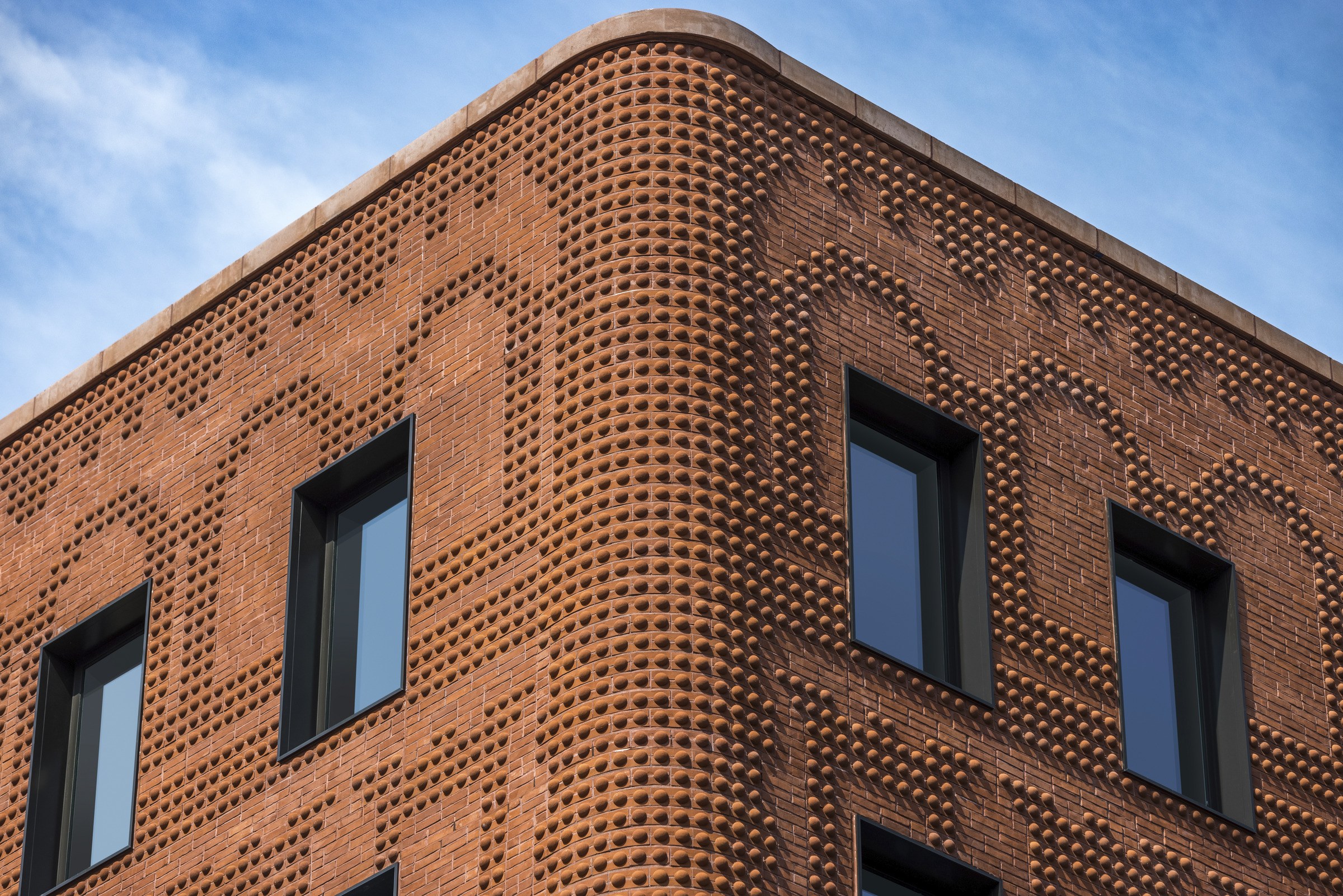Close-up view of a brick building's exterior corner and a detailed curved semi-circle pattern texture.