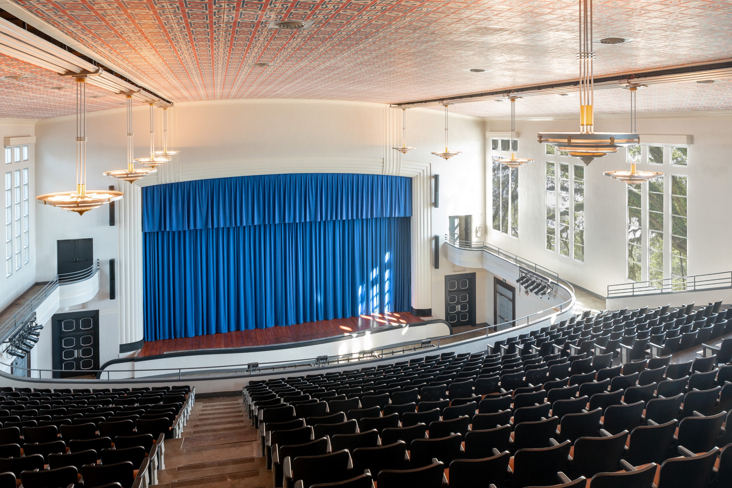 Interior view of an auditorium looking down at the stage from the back of the upper level of the auditorium.