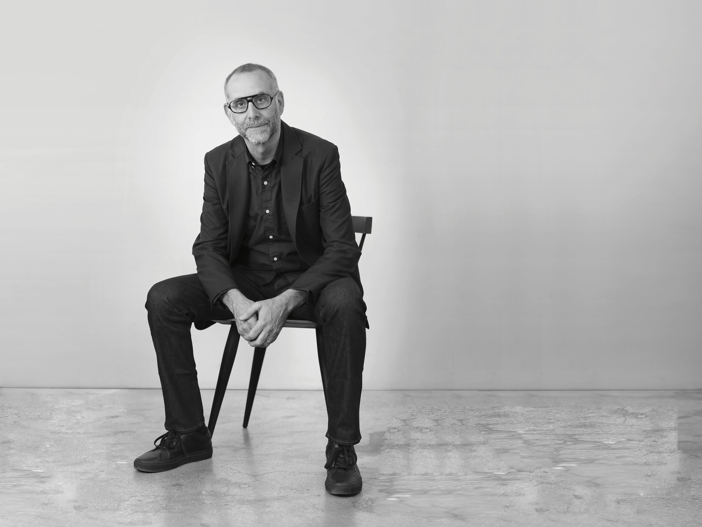 Portrait of Morris Adjmi sitting on a chair in an empty, minimalistic room