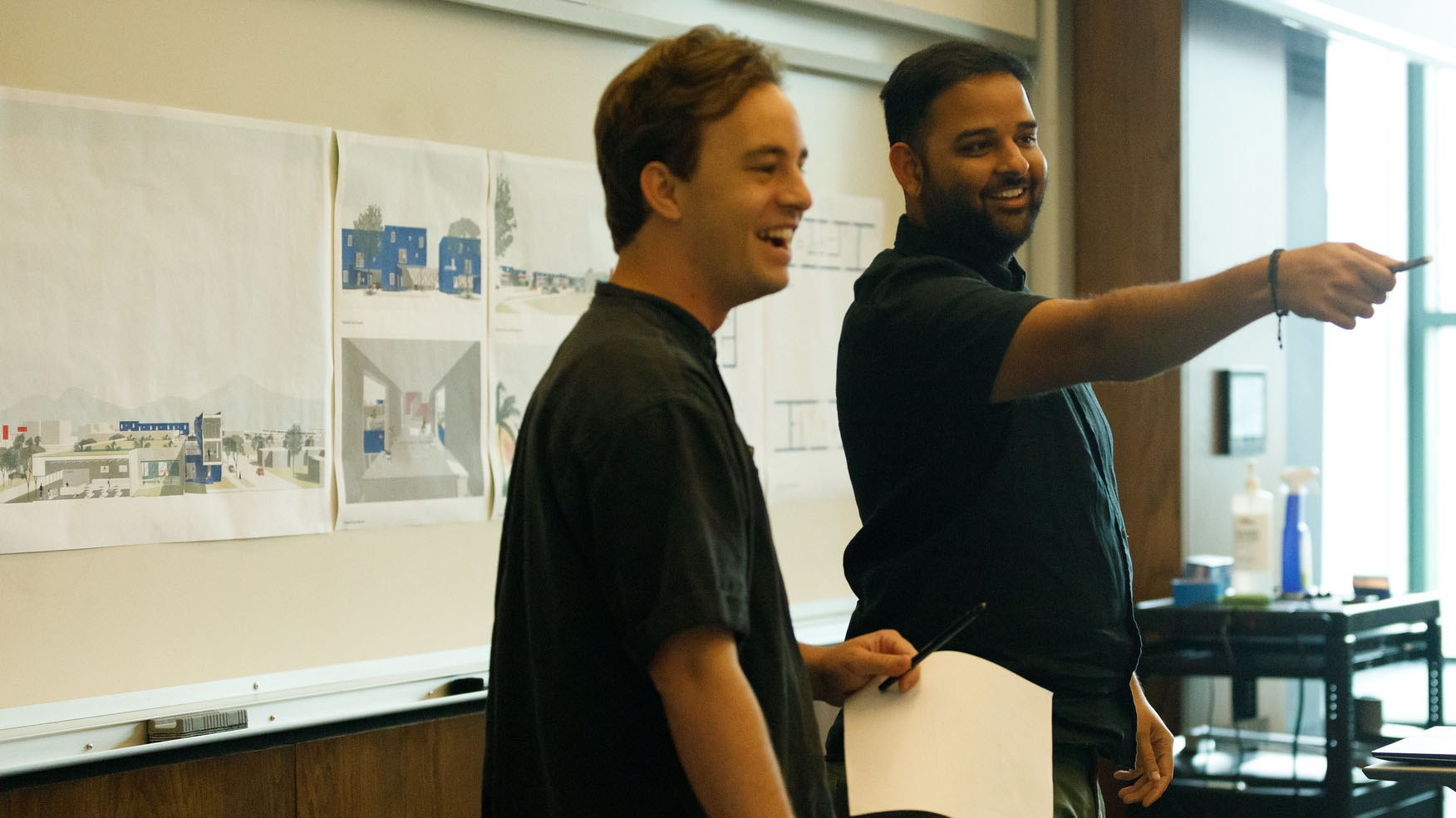 a professor and student stand next to each other, reviewing the students thesis project