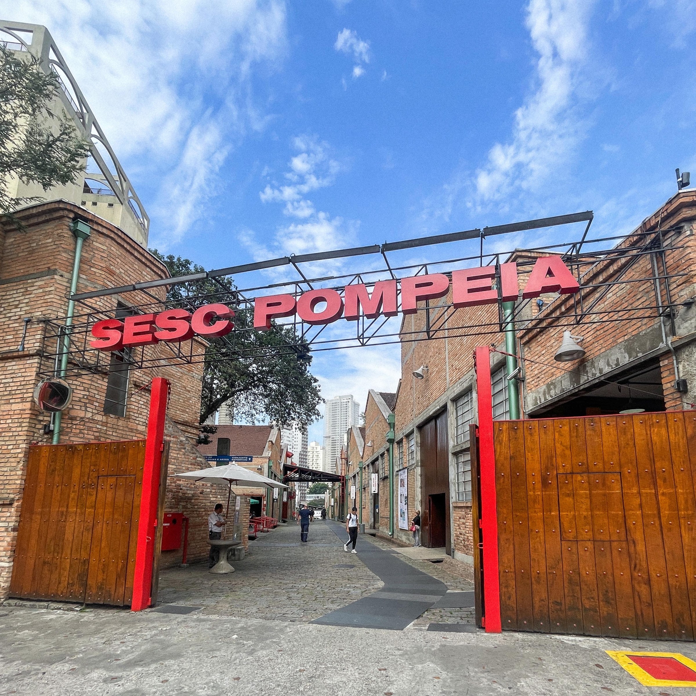 Photo of a entryway to a pedestrian path in a urbanized area with the words "Sesc Pompeia" above the entrance in Sao Paolo, Brazil.