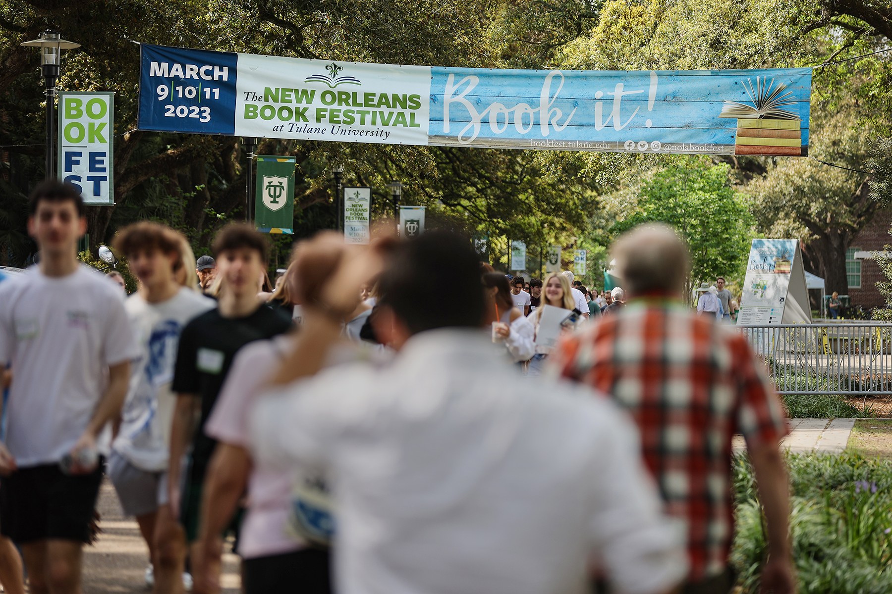 People walking through Tulane's campus under a banner promoting New Orleans Book Festival