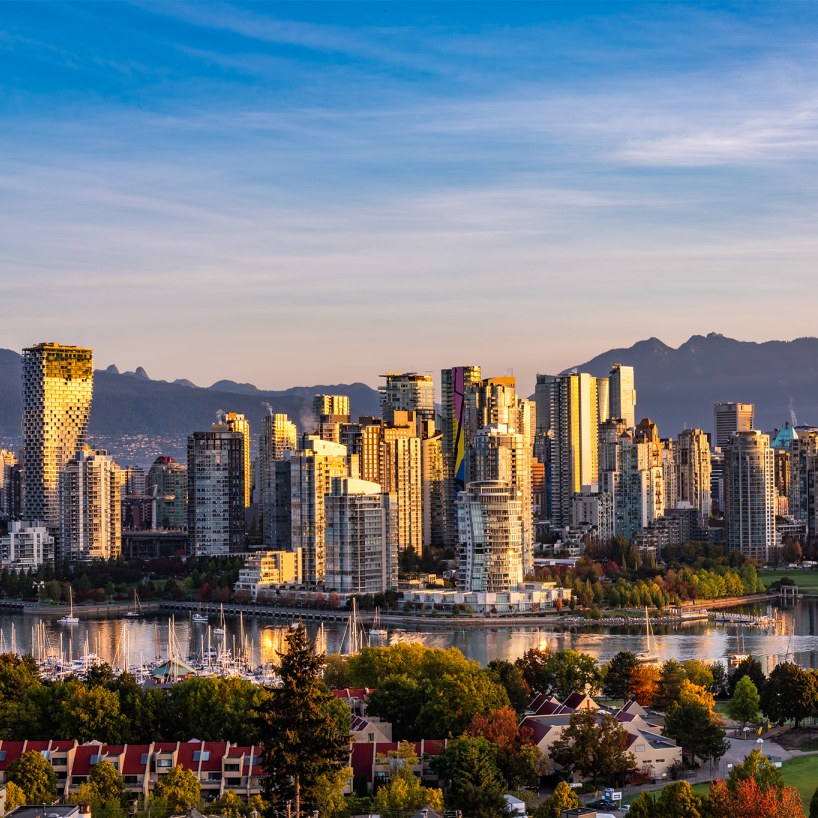 Skyline of Vancouver, British Columbia, Canada, with a mountain range behind downtown's tall buildings and water front properties.