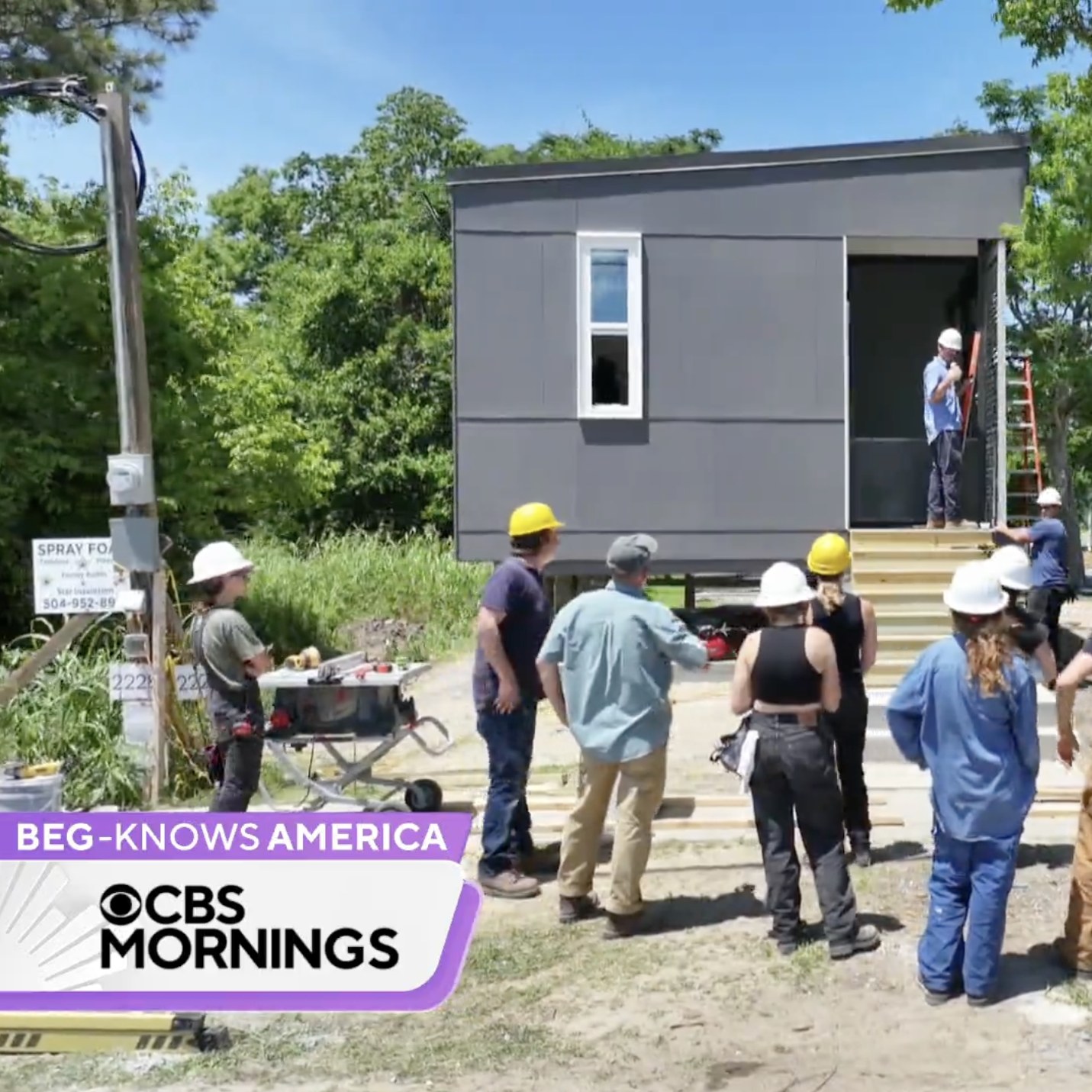 Screenshot of CBS News video of the exterior of a small home with students in hardhats standing in front.