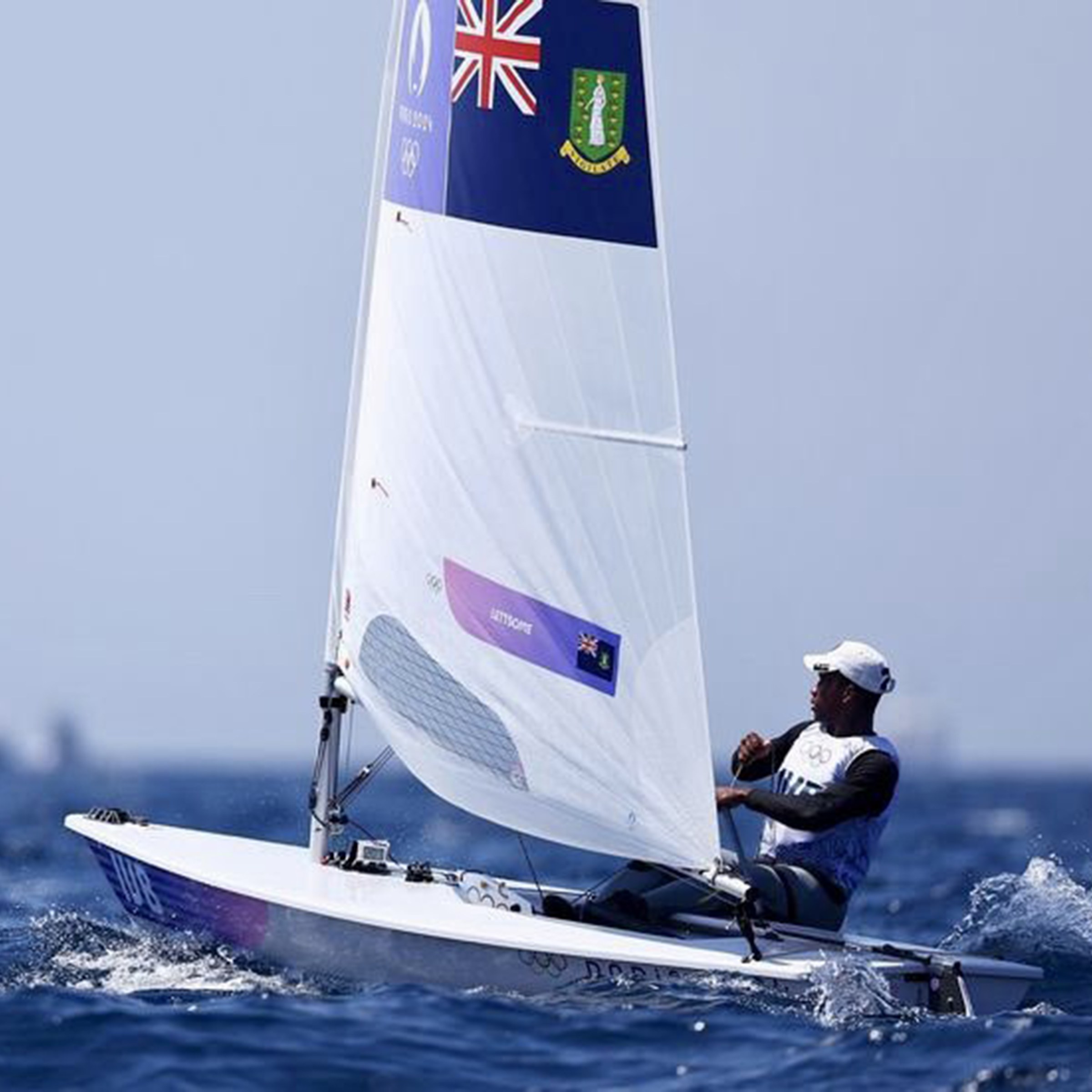 Close up of Thad Lettsome leaning back while sailing a single-person boat in open water.