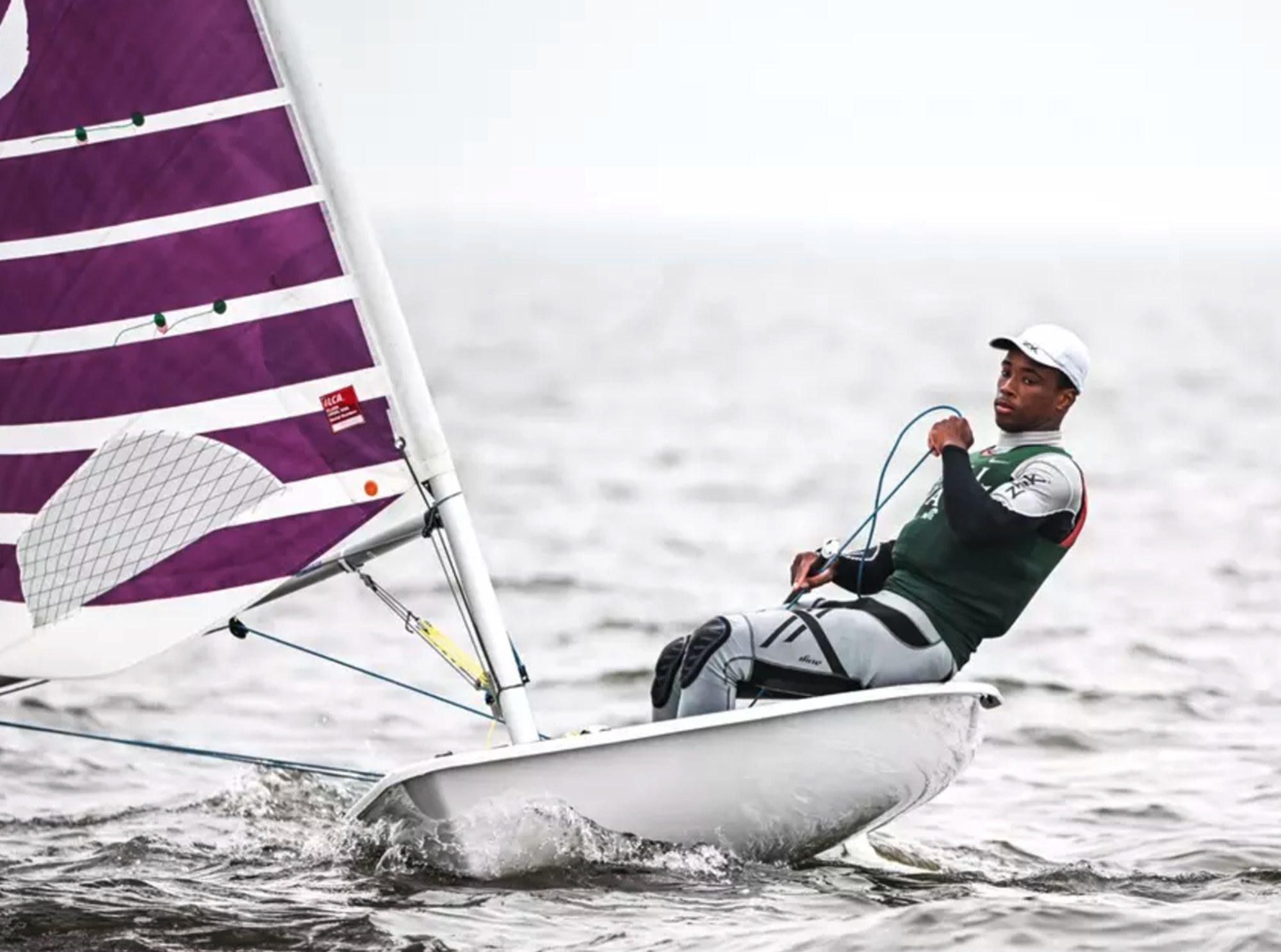 Close up of Thad Lettsome leaning back while sailing a single-person boat in open water.