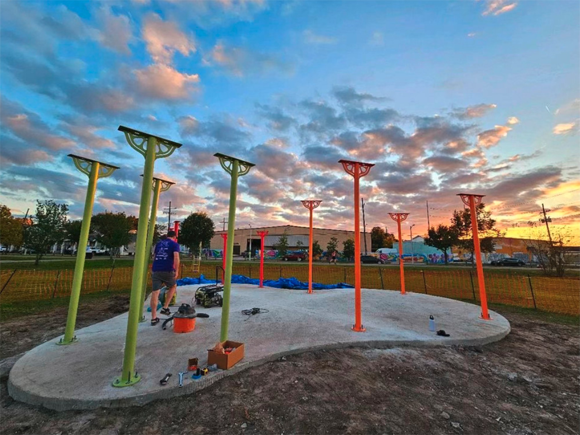 Pillars for an outdoor pavilion are erected in a concrete slab, the future classroom and farm stand space for an urban farm nonprofit.