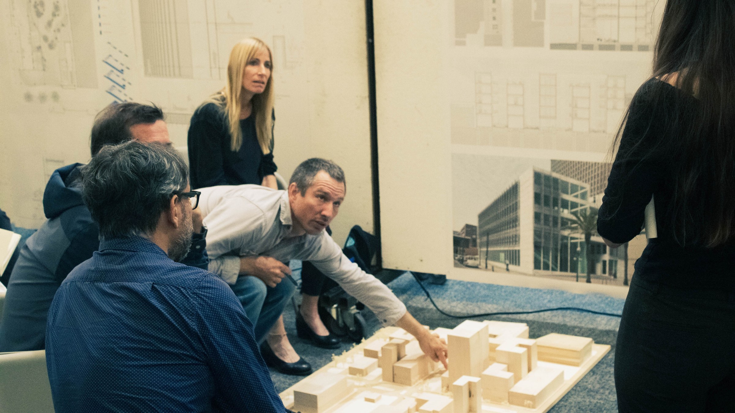 Three faculty and guest reviewers point to and share feedback about a site model to a student starting in the rightside foreground.