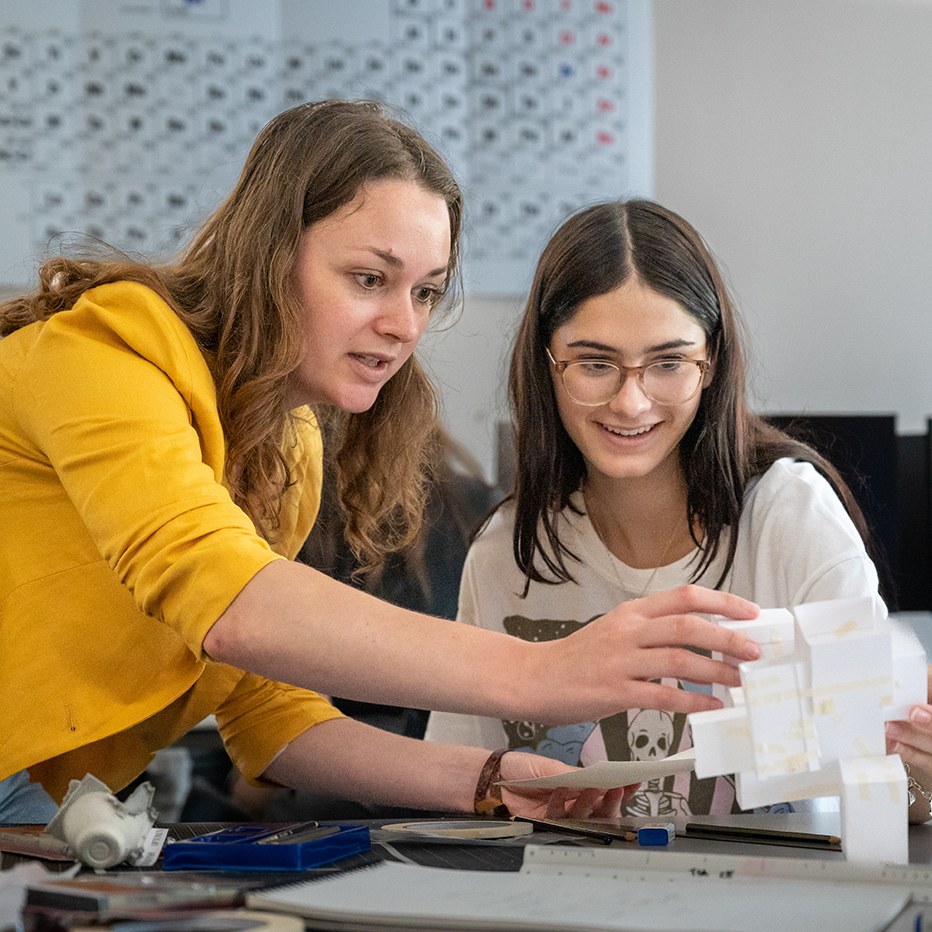Faculty and student look at and hold a 3D-printed resin model of a geometric structure.
