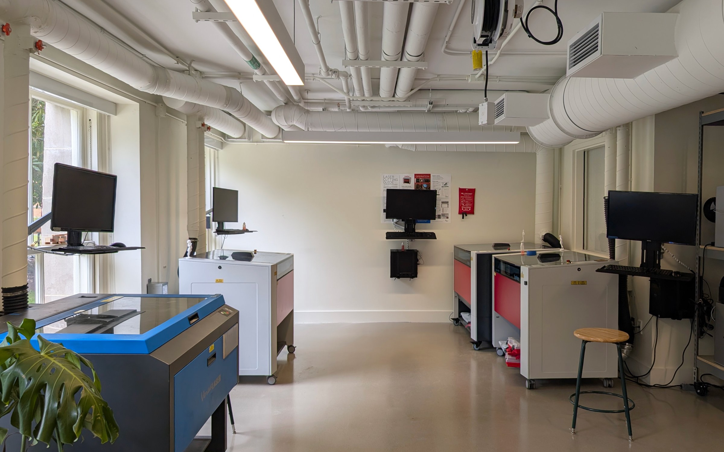 one point perspective view of the Laser Lab. 1 blue laser cutter in the foreground and 3 red laser cutters in the background