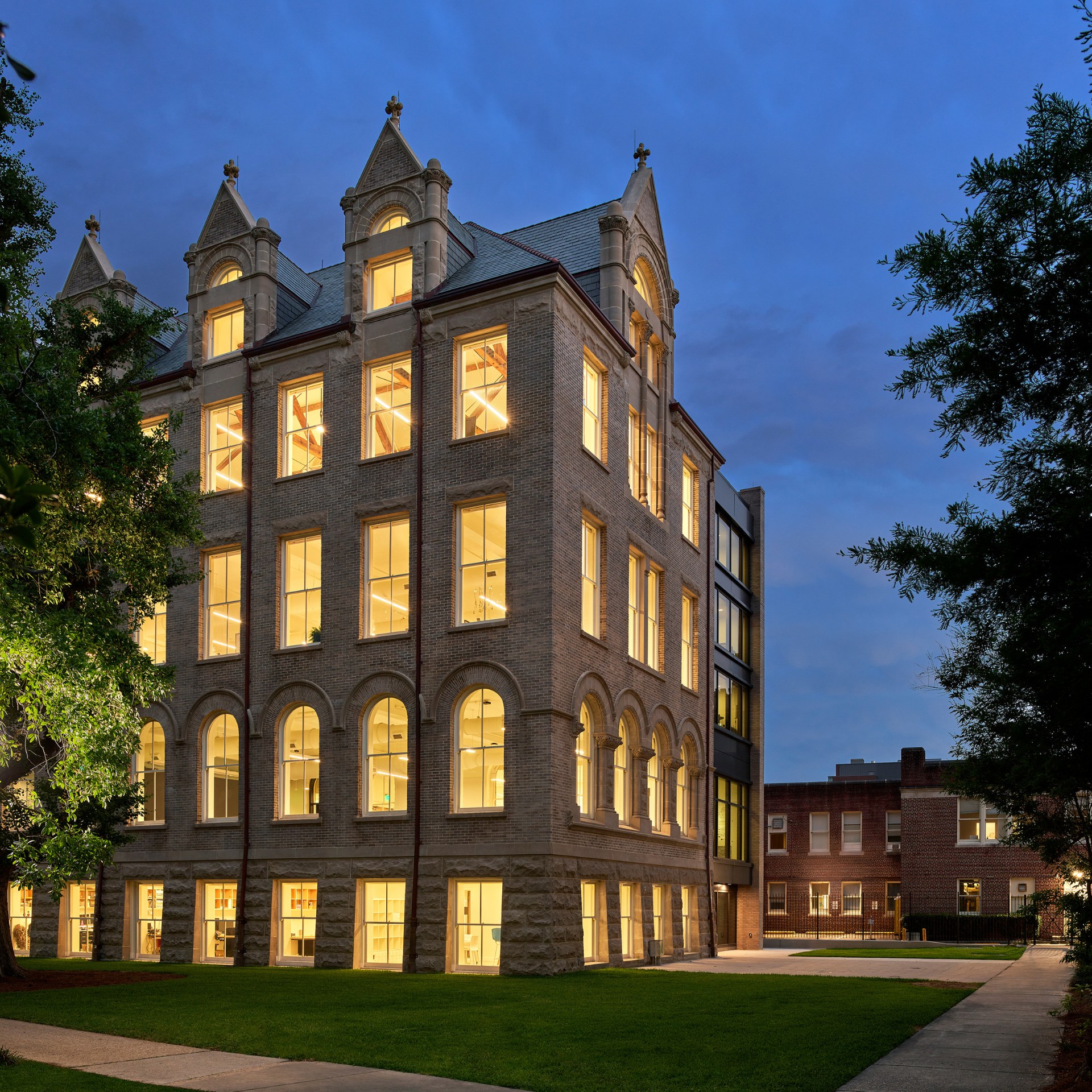 Full view of Richardson Memorial Hall's southwest corner with all interior lights on at night.