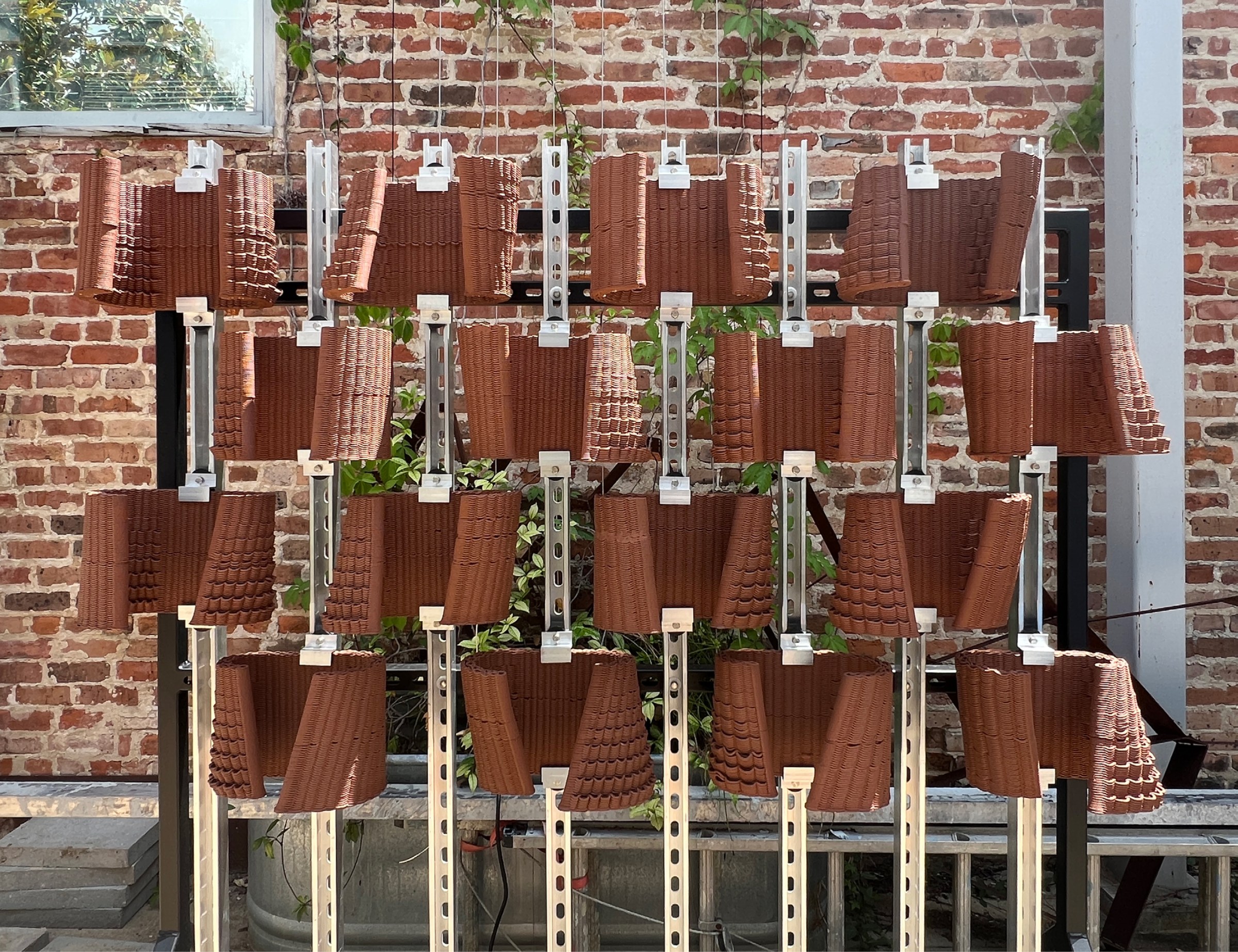 Pulled-back view of a facade system that uses interconnected ceramic vessels for water management.