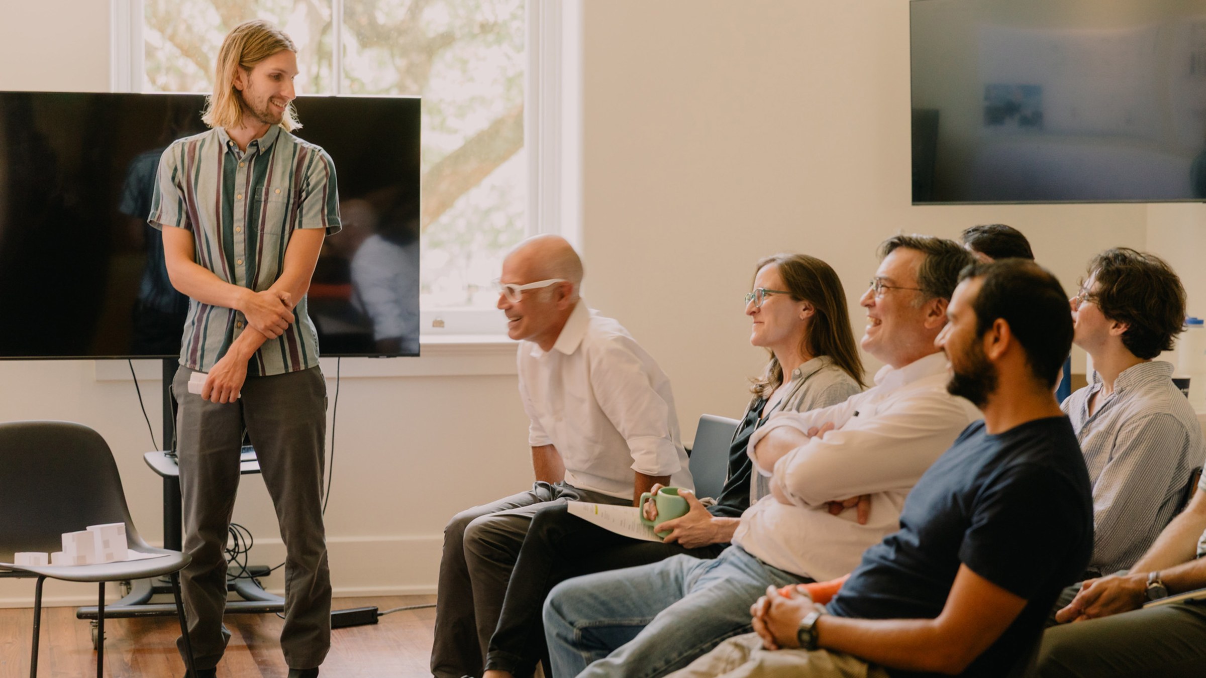 Faculty sit in a row and laugh while on a review panel for a student's work.