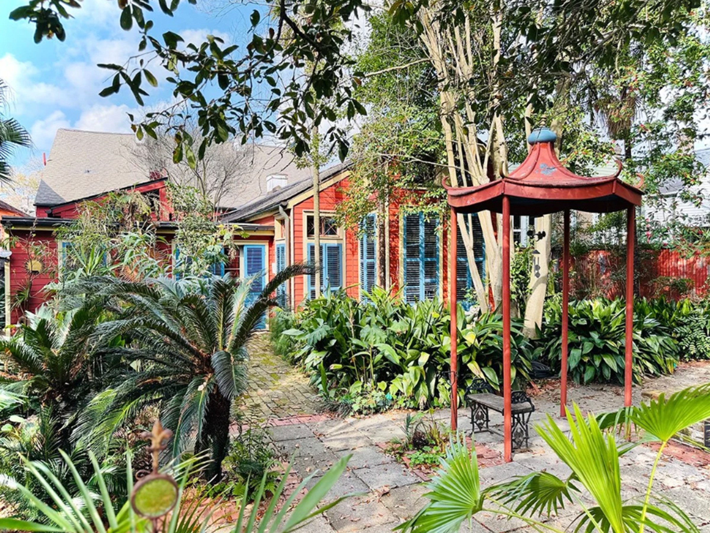 The back of Gene Cizek's house and backyard, with a cobblestone path and an orange gazebo that matches the house's color.
