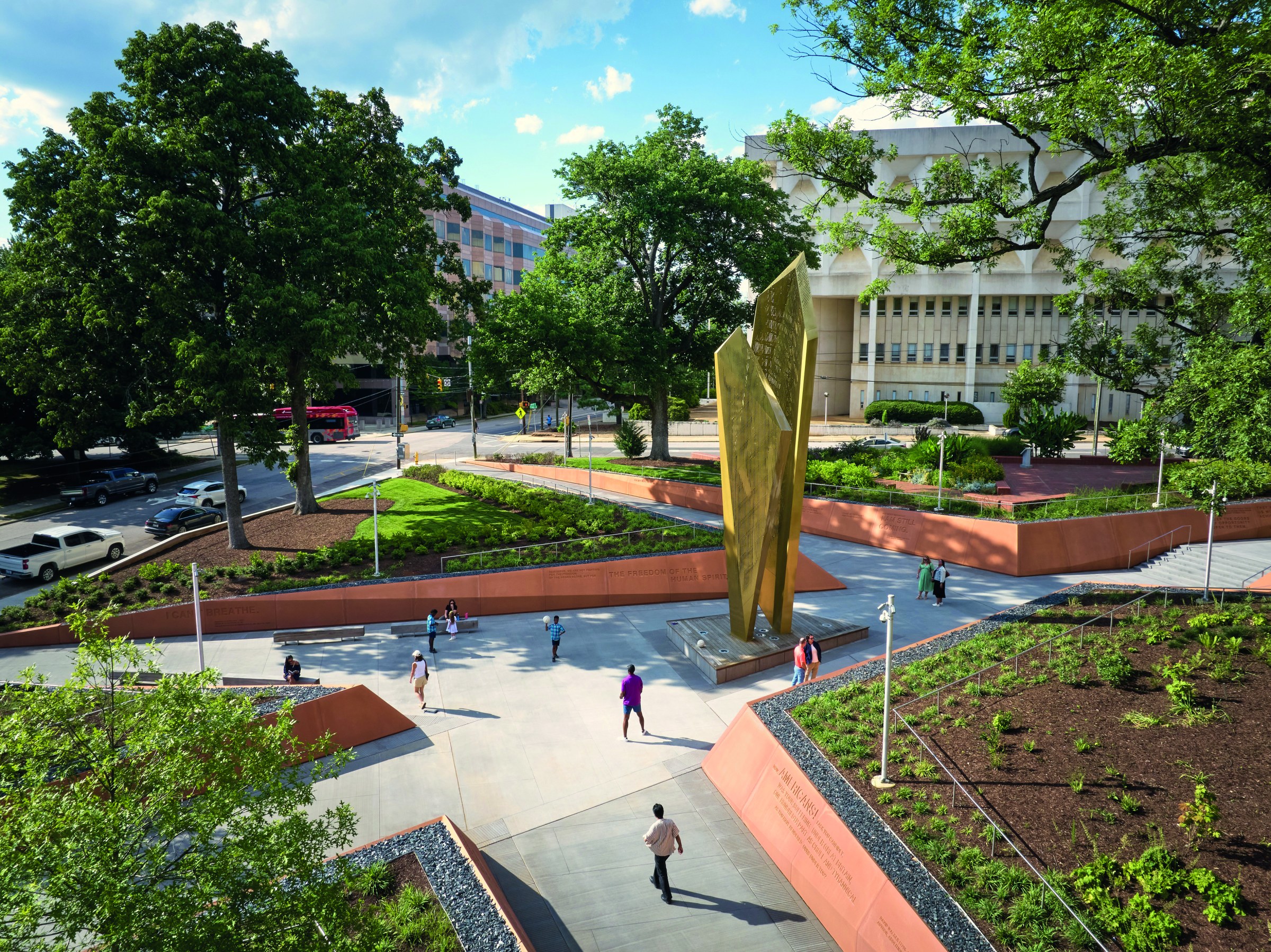Outdoor render of a public space. Greenery is on the corners and there is a walking path in the center.