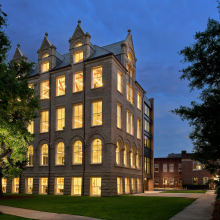 Full view of Richardson Memorial Hall's southwest corner with all interior lights on at night.